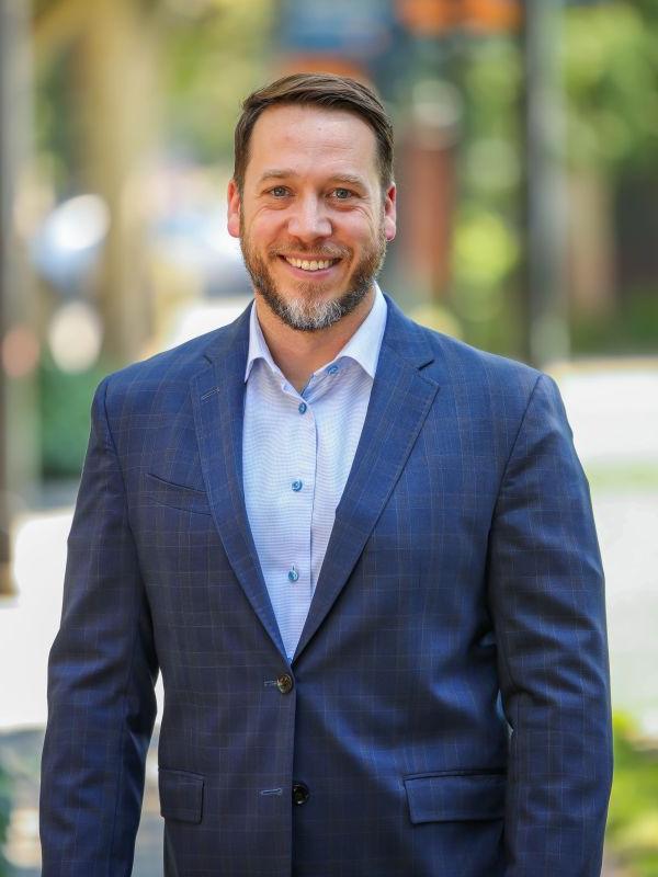 Man in blue suit smiles for a headshot 